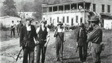 Three miners with federal soldier prepare to surrender weapons.
